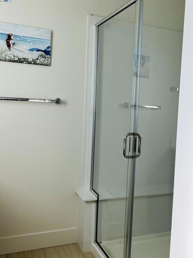 bathroom with wood-type flooring and a shower with door