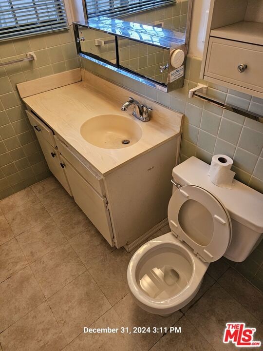 bathroom featuring tile patterned flooring, tile walls, and vanity