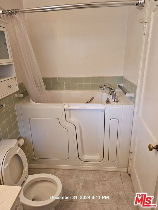 bathroom featuring toilet, tile patterned flooring, a washtub, and vanity