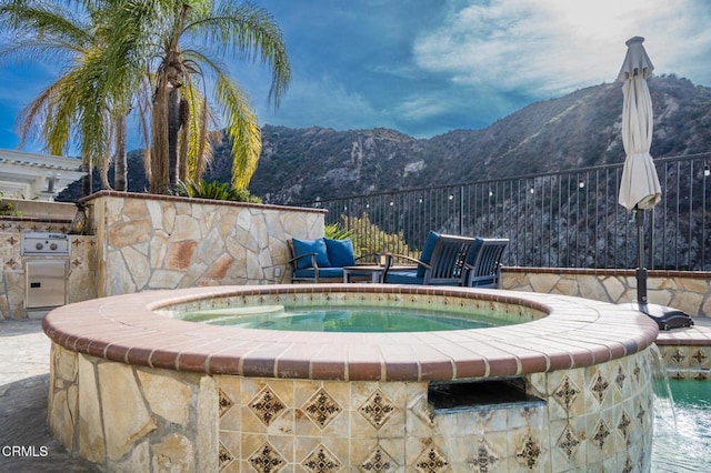 view of swimming pool featuring a mountain view, pool water feature, and a grill