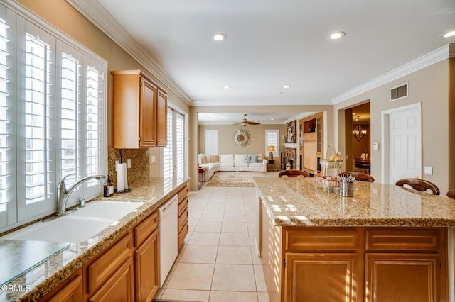 kitchen featuring a center island, light tile patterned floors, ornamental molding, ceiling fan with notable chandelier, and light stone counters