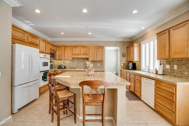 kitchen with a center island, light stone countertops, sink, stainless steel appliances, and a breakfast bar area