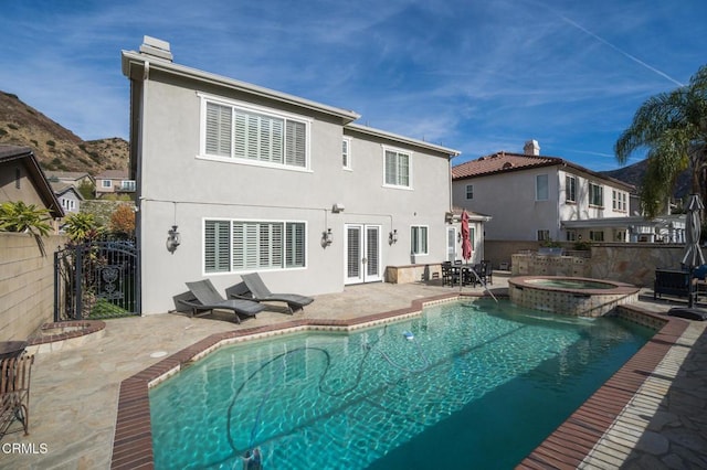 rear view of property featuring a mountain view, a pool with hot tub, french doors, and a patio