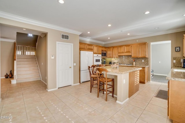 kitchen with a center island, white appliances, ornamental molding, and light tile patterned floors