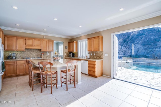 kitchen with crown molding, white dishwasher, a kitchen island, backsplash, and a breakfast bar area