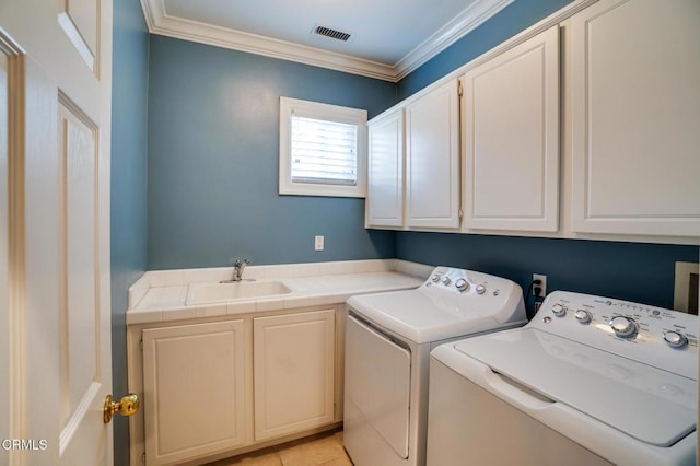 washroom with crown molding, washing machine and clothes dryer, light tile patterned floors, sink, and cabinets