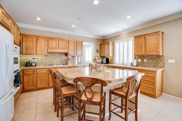 kitchen with light stone countertops, a center island, crown molding, and light tile patterned flooring