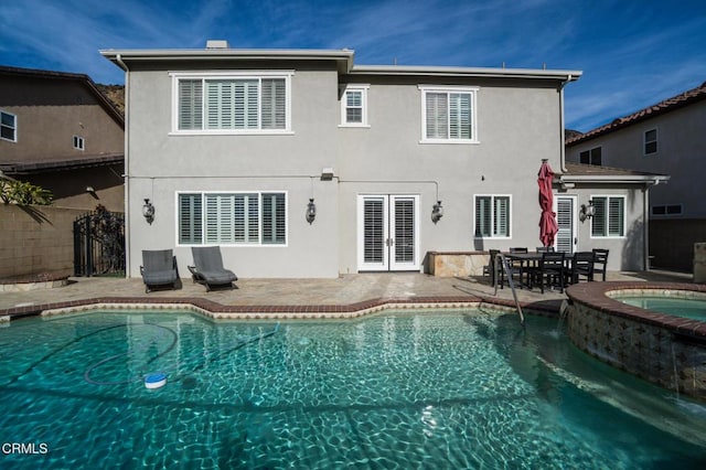 back of property featuring a patio, a swimming pool with hot tub, and french doors