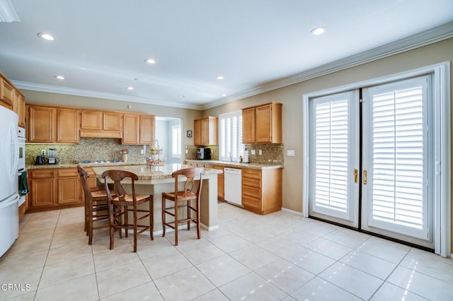 kitchen with white dishwasher, tasteful backsplash, light stone countertops, a kitchen bar, and a center island