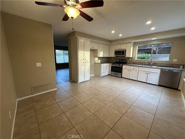 kitchen featuring sink, white cabinets, stainless steel appliances, and light tile patterned flooring