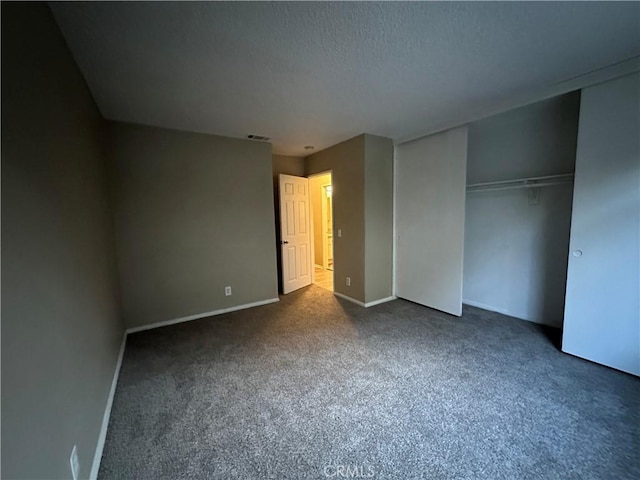 unfurnished bedroom featuring dark carpet, a closet, and a textured ceiling