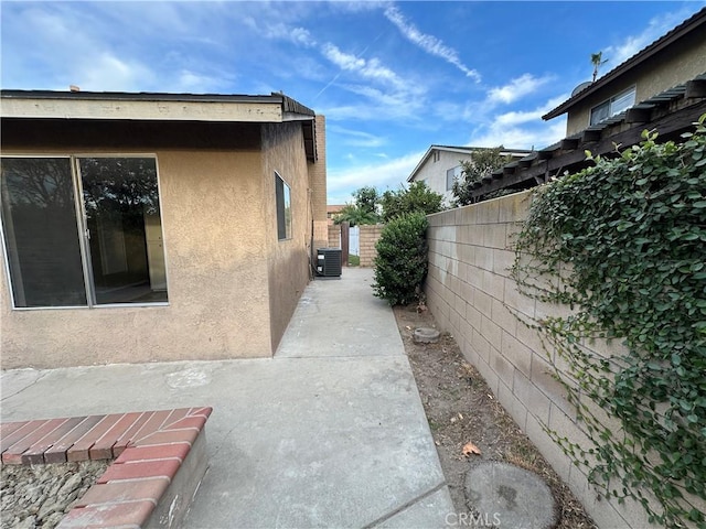 view of side of property with a patio area and central air condition unit