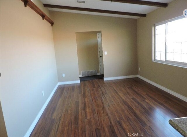 spare room featuring dark hardwood / wood-style floors and beamed ceiling