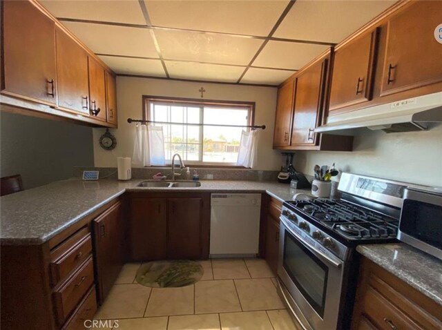 kitchen with dishwasher, gas stove, sink, light tile patterned flooring, and a drop ceiling