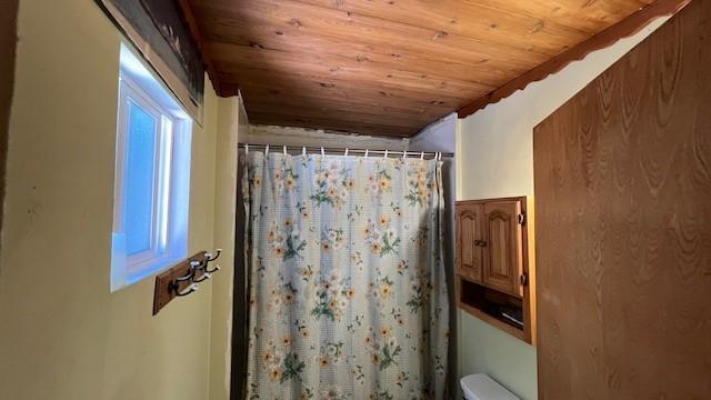 bathroom featuring vaulted ceiling, wooden ceiling, walk in shower, and toilet