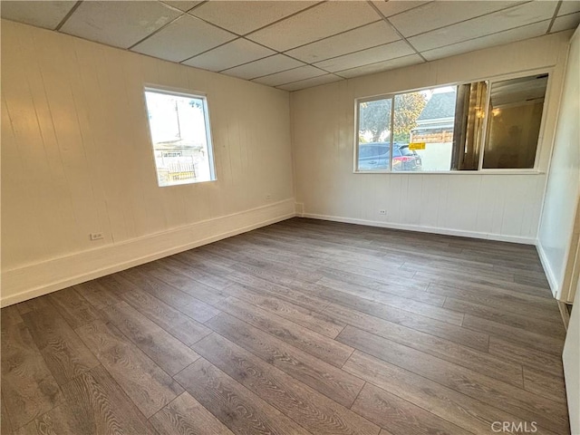 unfurnished room with a paneled ceiling and wood-type flooring