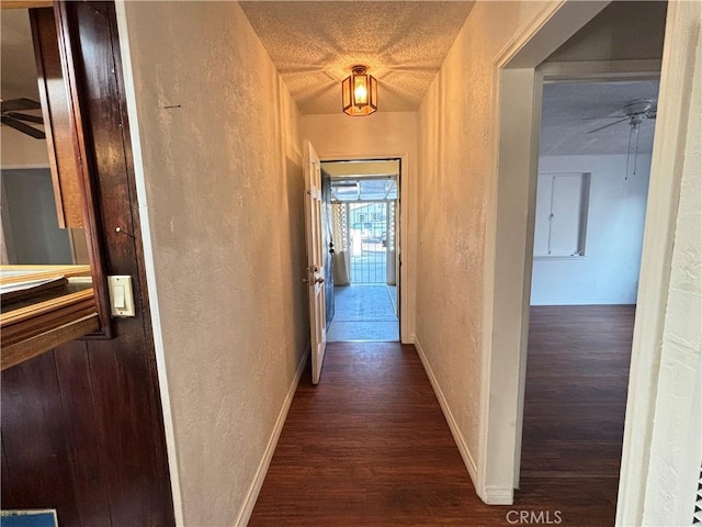 corridor with a textured ceiling and dark hardwood / wood-style floors