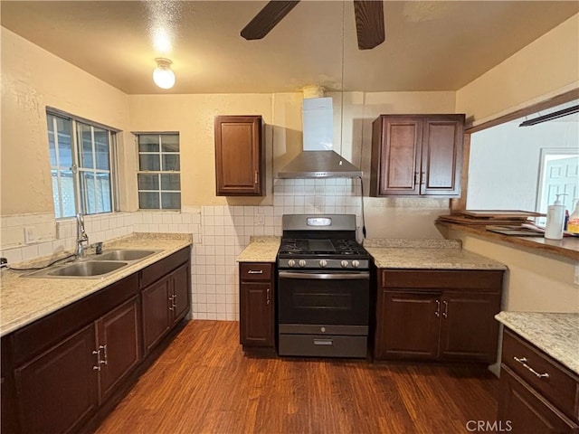 kitchen featuring sink, stainless steel range with gas cooktop, dark hardwood / wood-style flooring, dark brown cabinetry, and wall chimney exhaust hood