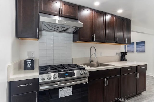 kitchen featuring light wood-type flooring, sink, gas stove, and dark brown cabinetry