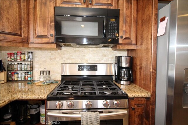 905 Madera Ln, Lake Arrowhead, CA 92352 - kitchen featuring brown cabinetry, stainless steel appliances, backsplash, and light stone counters