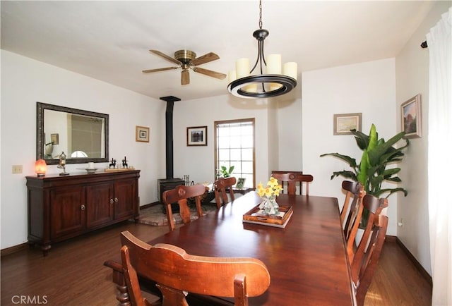 dining area with ceiling fan, a wood stove, and dark hardwood / wood-style floors