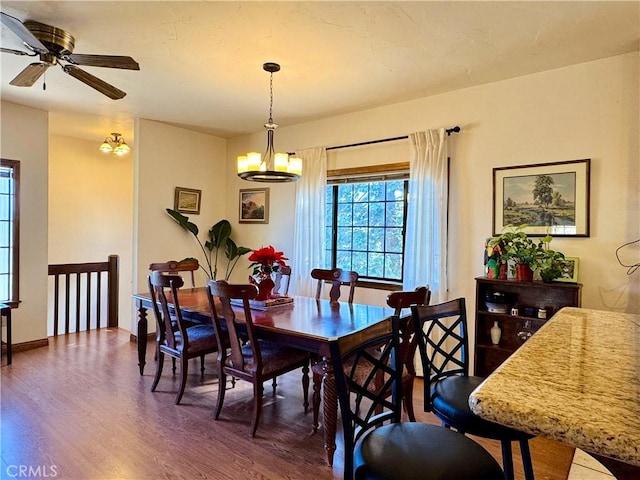 dining room featuring ceiling fan with notable chandelier and hardwood / wood-style flooring