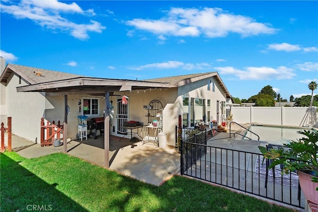 rear view of property featuring a fenced in pool, a patio area, and a lawn