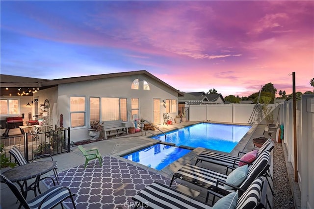 pool at dusk featuring a patio area