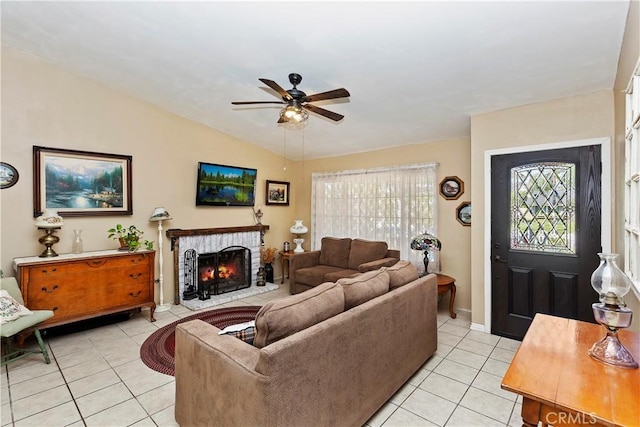 living room featuring lofted ceiling, ceiling fan, a brick fireplace, a wealth of natural light, and light tile patterned flooring