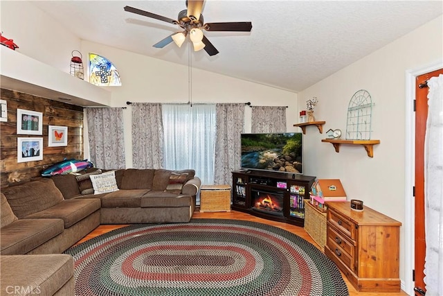 living room with lofted ceiling, ceiling fan, a textured ceiling, and wood-type flooring