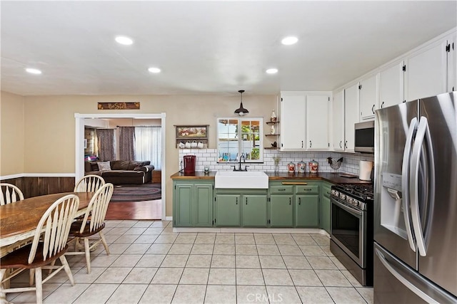 kitchen featuring white cabinets, stainless steel appliances, sink, hanging light fixtures, and green cabinetry