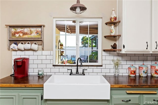 bar with decorative backsplash, sink, green cabinets, and butcher block counters