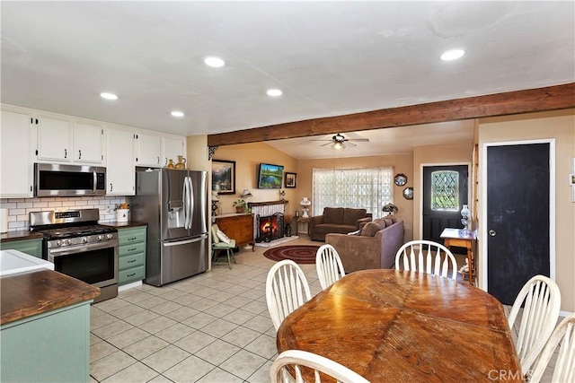 kitchen featuring ceiling fan, backsplash, lofted ceiling with beams, white cabinetry, and stainless steel appliances