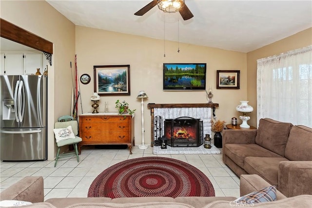 living room featuring lofted ceiling, light tile patterned floors, ceiling fan, and a brick fireplace