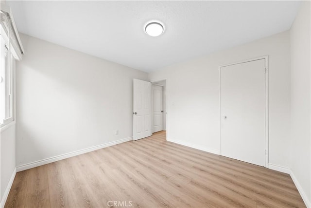 unfurnished bedroom with a closet and light hardwood / wood-style floors