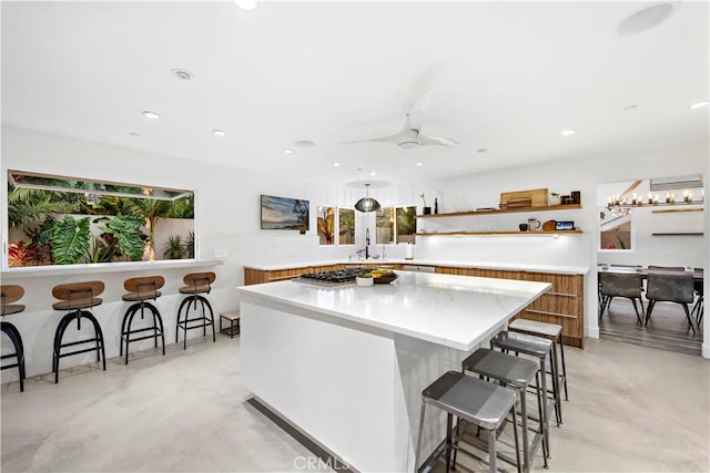 kitchen featuring a kitchen breakfast bar, ceiling fan, plenty of natural light, and a center island