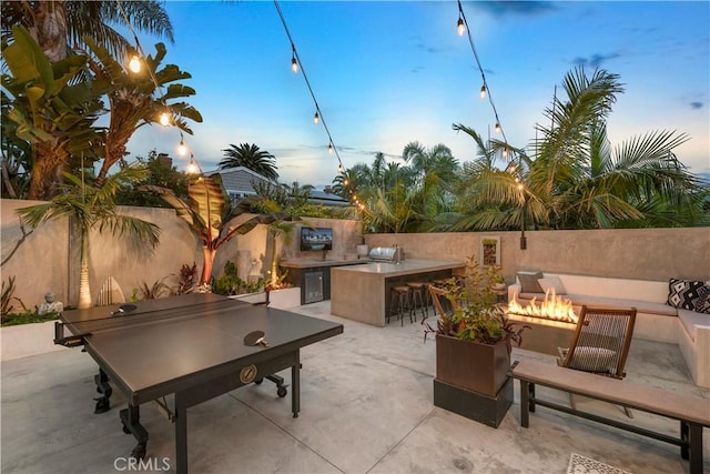 view of patio with area for grilling, an outdoor fire pit, and exterior bar