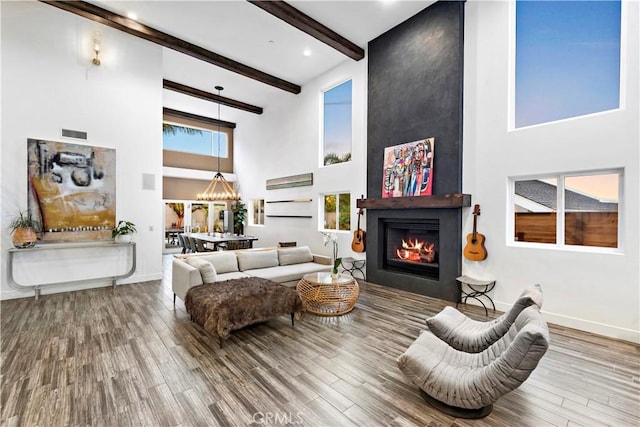 living room with a large fireplace, a towering ceiling, hardwood / wood-style floors, and beamed ceiling