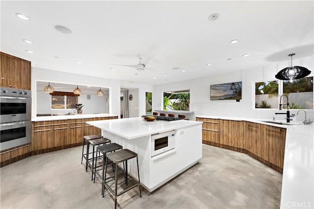 kitchen featuring decorative light fixtures, ceiling fan, white microwave, a kitchen breakfast bar, and double oven