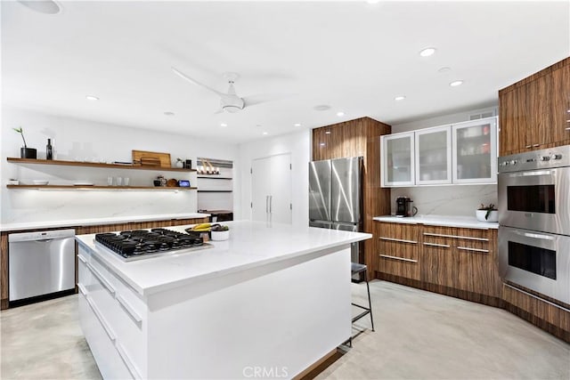 kitchen with ceiling fan, a center island, a breakfast bar, stainless steel appliances, and white cabinets