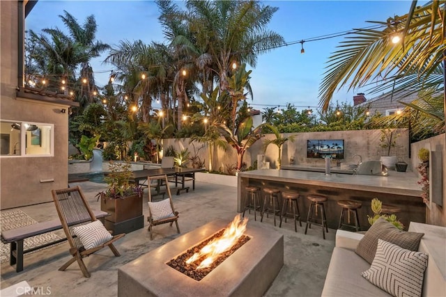 patio terrace at dusk with an outdoor fire pit and an outdoor bar