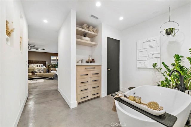 bathroom with ceiling fan, a bathtub, and concrete flooring