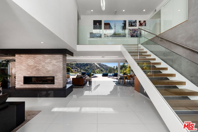 stairs featuring a large fireplace, tile patterned flooring, and a high ceiling