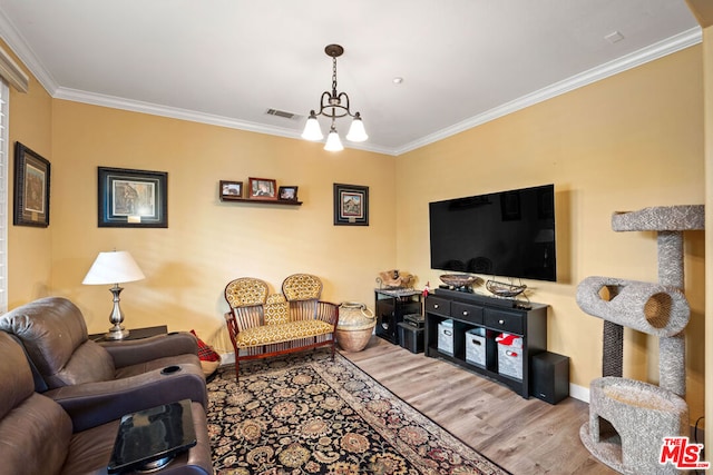 living room with ornamental molding, a notable chandelier, and light wood-type flooring