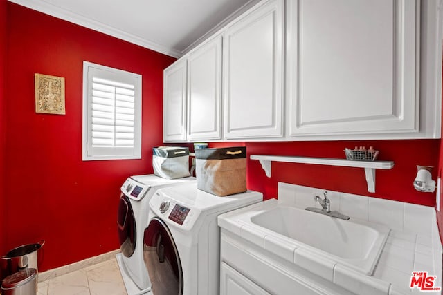 laundry room with cabinets, sink, ornamental molding, and washing machine and clothes dryer