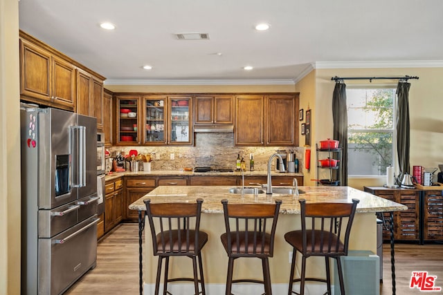 kitchen featuring light stone countertops, sink, ornamental molding, and high end refrigerator