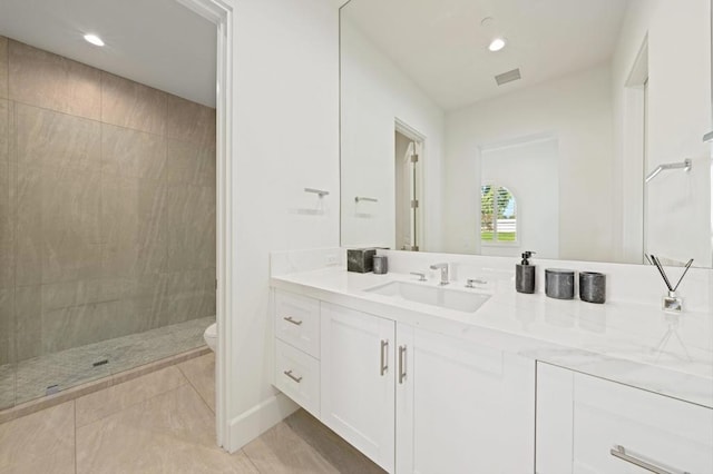 bathroom with tile patterned floors, toilet, vanity, and a tile shower