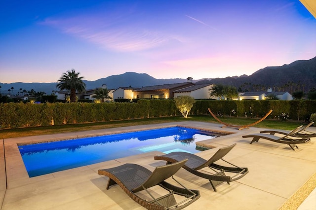 pool at dusk featuring a mountain view and a patio area