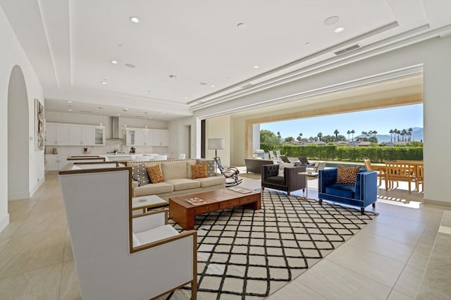 living room with a tray ceiling and light tile patterned floors