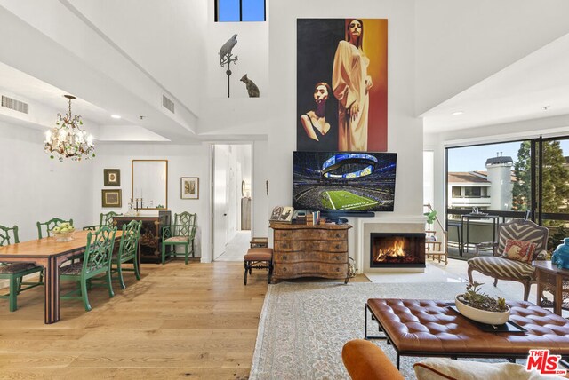 living room with a chandelier, a towering ceiling, and light hardwood / wood-style flooring